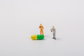 Macro close-up of miniature people and oral medicine on white background