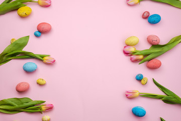 Beautiful pink tulips and colored Easter eggs on a pink background.