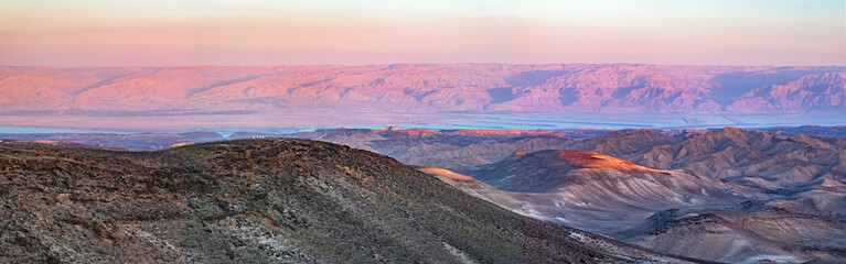 colorful panorama of the sun setting on the moav mountains in jordan and the dead sea from the negev desert hills near Arad in Israel