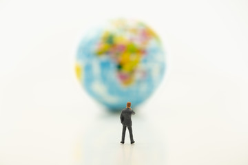 Businessman miniature people figure thinking and looking to mini world map ball on white table background with copy space using for business,marketing, and financial concept.