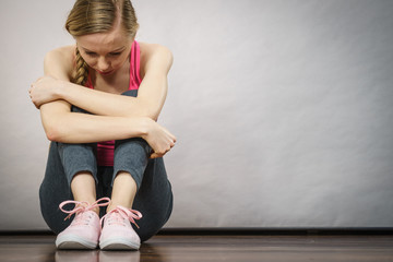 Sad depressed young teenage girl sitting by wall