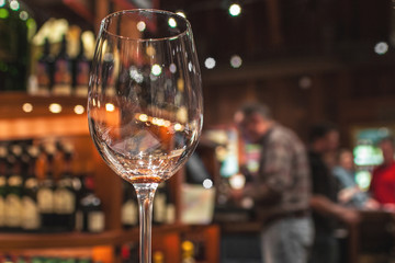 Empty wine glass with blurry background of people at the bar