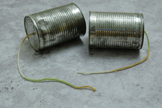Tin can phones on gray background with the rope got cut off. Concept disconnected communication