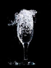 Water with splashes in a glass on a black background