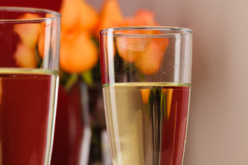 Close up photo of champagne glasses with roses in a vase