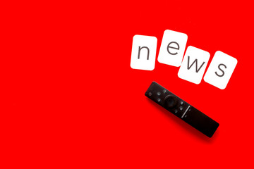 News concept. TV remote on red background top-down copy space