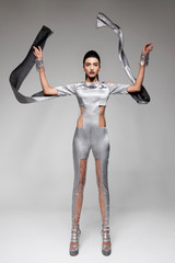 brunette model in futuristic stylish gray transparent detailed jumpsuit. white background.