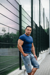 Sports guy stands near the sports field. Bodybuilding