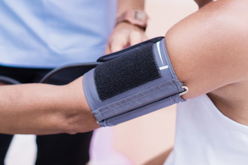 Arm of Asian man undergoing blood pressure measurement