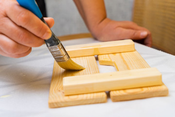 Girl varnishes a wooden detail.