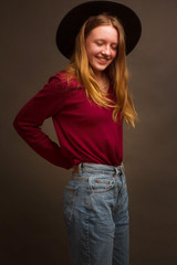 portrait of a girl in the Studio with painted blonde hair, in a red sweater and blue jeans.