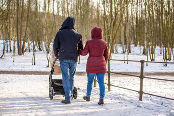 A married couple rolls a child in a wheelchair in the winter Park