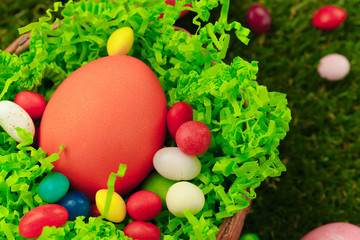 Close up photo of colored Easter eggs and candies on grass