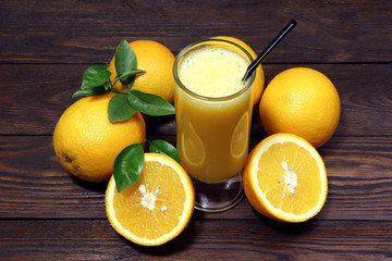 A glass of fresh orange juice and orange fruits on a wooden table. Healthy food.