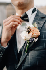 Groom in tuxedo and bowtie correct his bowtie. Wedding. Details