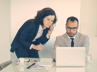 Serious business colleagues using gadgets while working on project together. Business man and woman...