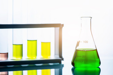 chemical liquid containing in flask with lab glassware on white background, lab research and...