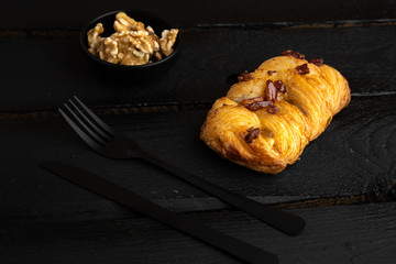 small puff pastry cake with nuts on black wooden background