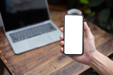 Mockup image blank white screen cell phone.man hand holding texting using mobile on desk at coffee shop.background empty space for advertise text.people contact marketing business,technology