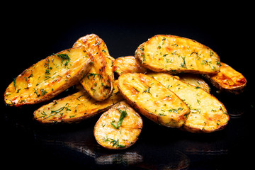 Potatoes with greens on a black background..