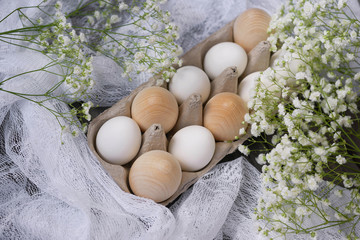 Happy Easter. White chicken eggs, wooden eggs in a stand on a wooden background with white...