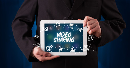 Young business person working on tablet and shows the inscription: VIDEO SHARING