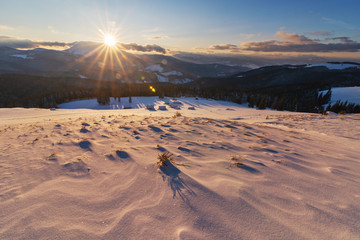 Charming snow-capped houses on a mountain Carpathian mountain valley, with magnificent views of peaks in winter.