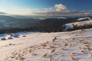 Charming snow-capped houses on a mountain Carpathian mountain valley, with magnificent views of peaks in winter. © reme80