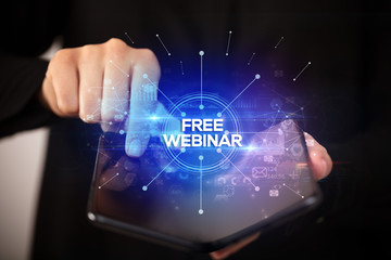 Businessman holding a foldable smartphone with FREE WEBINAR inscription, new business concept