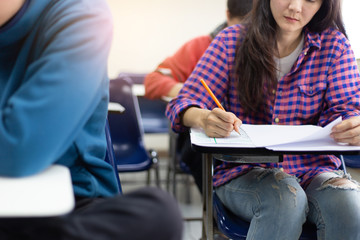 high school,university student study.hands holding pencil writing paper answer sheet.sitting lecture chair taking final exam attending in examination classroom.concept scholarship for education abroad