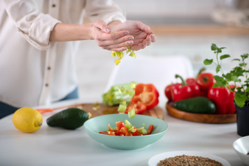 Obraz na płótnie Canvas Female hands pouring light green salad into a deep plate.