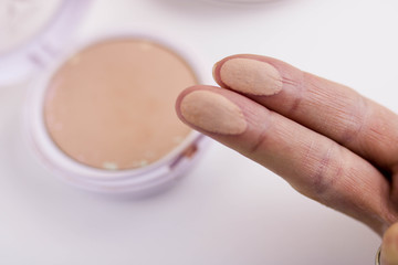 Swatches of powder palette on a woman's fingers. White background.