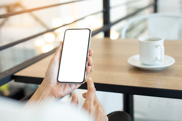 Mockup image blank white screen cell phone.woman hand holding texting using mobile on desk at coffee shop.background empty space for advertise text.people contact marketing business,technology