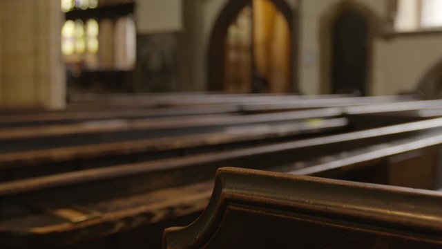 Medium low angle, tilting still shot of St. Mary's Church's wooden sitting benches against blurred interior background, Bridgewater, UK
