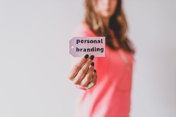 influencers and fame, girl holding Personal Branding message on price tag close to the camera shot at shallow depth of field