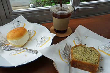 Close up French vanilla brioche doughnut and lemon poppy seed pound cake served with Iced black...