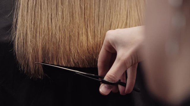 Hair salon girl haircuts. Close up 4K slow motion. Align the hair length