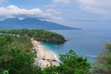 Beautiful landscape with a view of the lost beach in Bali. Virgin beach with white sand and white traditional fishing boats. The view from the top. Blue sky with clouds