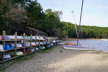 Fototapeta na wymiar dingy boat under water over winter racked one above on dry rack boats on sand lake beach