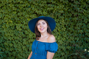 Young and beautiful brunette girl in dress and hat walking outdoor in the park. Nice, France. Summer vacation, traveling and tourism.