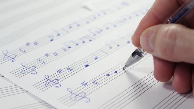 A musician-composer writes notes on a pentagram. Music, art, creative person, inspiration. Close up