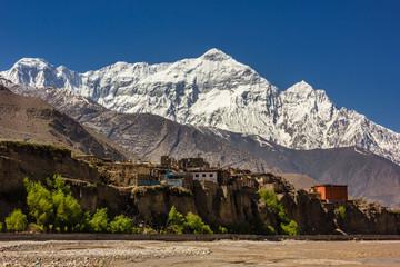 The Himalayan village of Kagbeni in Upper Mustang on the Annapurna Circuit trekking trail in Nepal with the snow covered Nilgiri North towering above it.