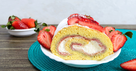 Sweet biscuit roll with strawberries and cream on a wooden background