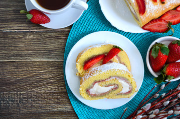 Sweet biscuit roll with strawberries and cream fresh berries and tea on a wooden background. The top view