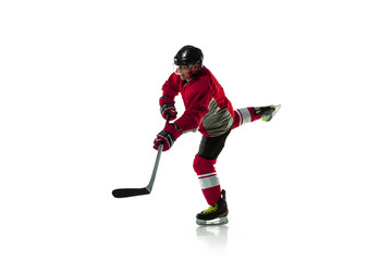 Fototapeta premium Leader. Male hockey player with the stick on ice court and white background. Sportsman wearing equipment and helmet practicing. Concept of sport, healthy lifestyle, motion, movement, action.