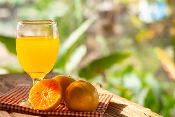 A glass of orange juice and citrus fruits on a wooden table