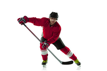 Obraz premium Scoring a goal. Male hockey player with the stick on ice court and white background. Sportsman wearing equipment and helmet practicing. Concept of sport, healthy lifestyle, motion, movement, action.