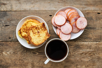 Breakfast with french toasts and sausage on a wooden background 