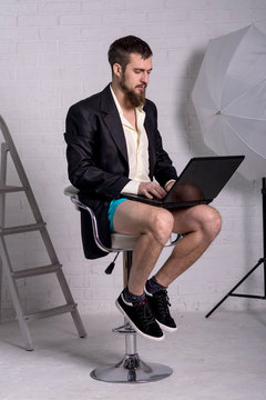 Man in a jacket and shorts is sitting with a laptop, the concept of remote work.