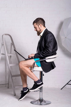 Man in a jacket and shorts is sitting with a laptop, the concept of remote work.